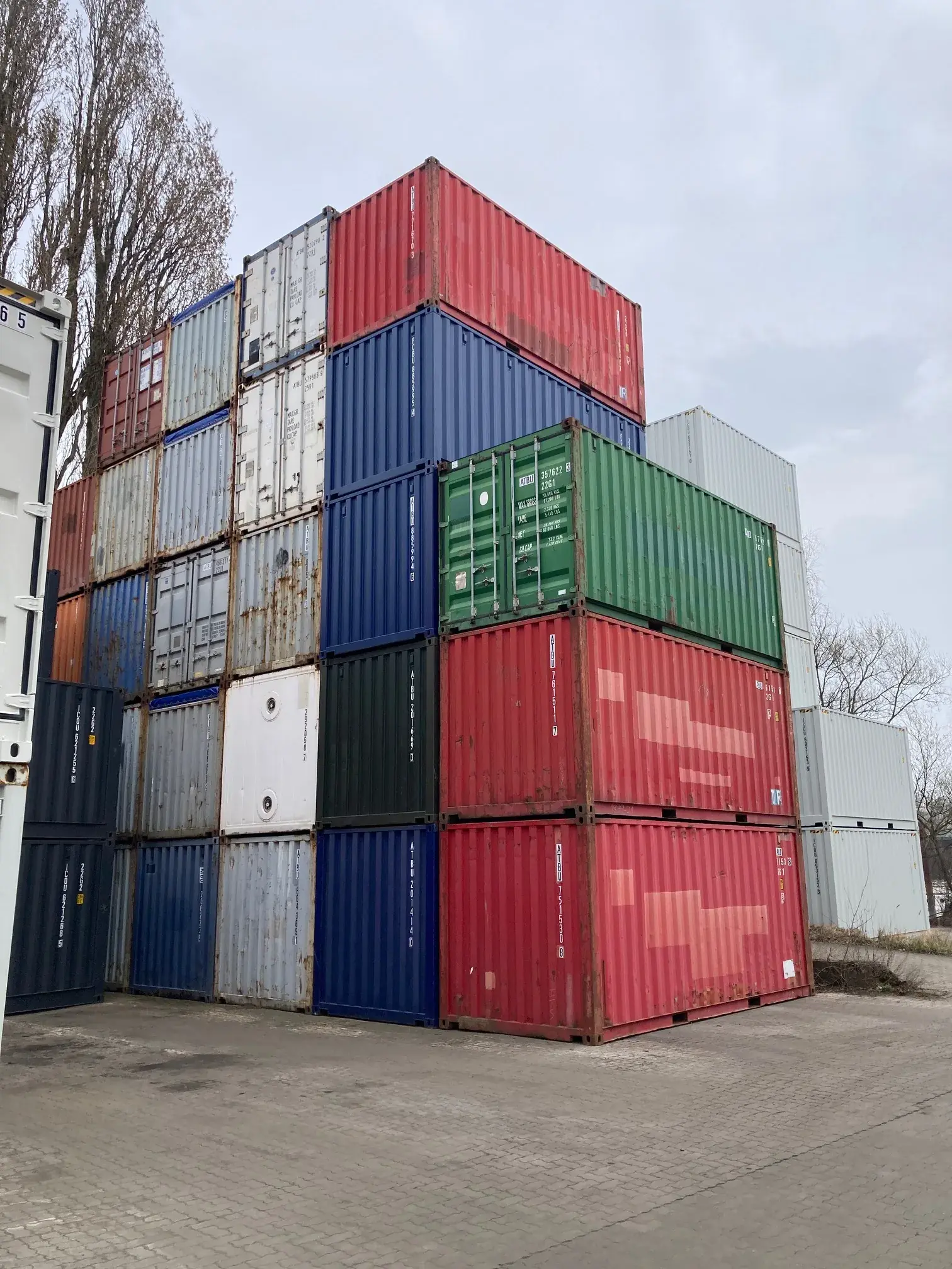 Gestapelte 20’-Seecontainer im Depot, verschiedene Farben und Zustände
